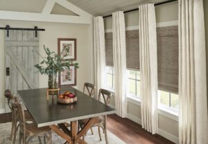 A dining room with a wall of windows with woven shades