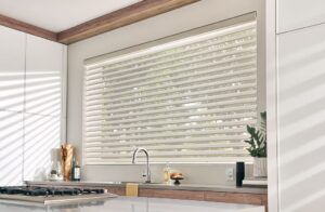 A kitchen window with white sheer shades